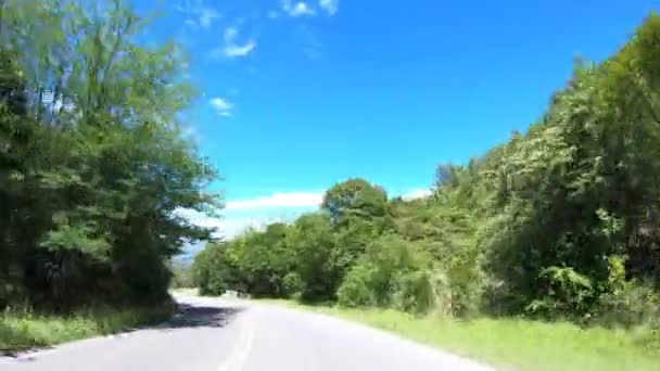 Conduciendo por un camino serpenteante a través de pastizales, colinas rocosas y paisajes boscosos. Viajando por ecosistemas nativos. Córdoba, Argentina — Vídeo de stock