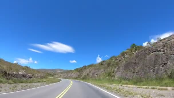 Conduciendo a través de serpentina carretera ascendiendo una montaña a través de galerías rocosas, pastizales y bosques. Secuencias de movimiento rápido. Córdoba, Argentina — Vídeo de stock