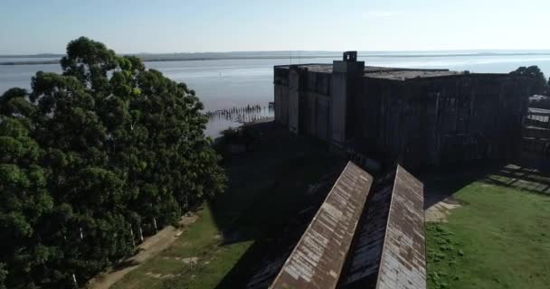 Escena aérea de drones del puerto viejo, grúa y construcción abandonada en la orilla de la ciudad de Fray Bentos, The Anglo. Volando sobre viejos cobertizos oxidados hacia el río. Unesco, Uruguay — Vídeos de Stock