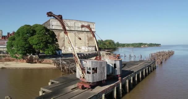 Scena dronów latających wokół starych drewnianych żurawi detal maszyn drewnianych i żelaznych. Porzucone konstrukcje portowe w tle. Unesco, Fray Bentos, Urugwaj — Wideo stockowe