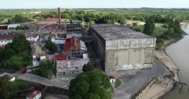 Aerial general view of old abandoned insutrial sheds, dock and cranes. Flying backwards to panoramic view of vintage constructions. The Anglo, Unesco, Fray Bentos, Uruguay