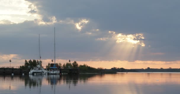 Segelbåtar förtöjda till trädocka vid solnedgången. Orange reflektioner över vatten. Lugn atmosfär. Fridfull rörelse av vatten, naturlig grön miljö i bakgrunden. Villa Soriano, Uruguay — Stockvideo