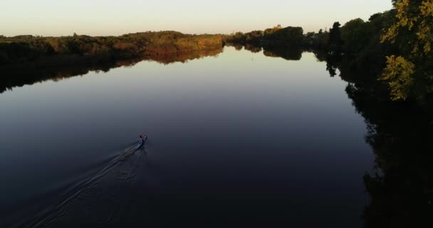 Aerial scene following men paddling at kayak on calm river that reflects sky and woods of the shore. Person breaking tranquil water surfac. San salvador river, Dolores city, Soriano, Uruguay — Stock Video