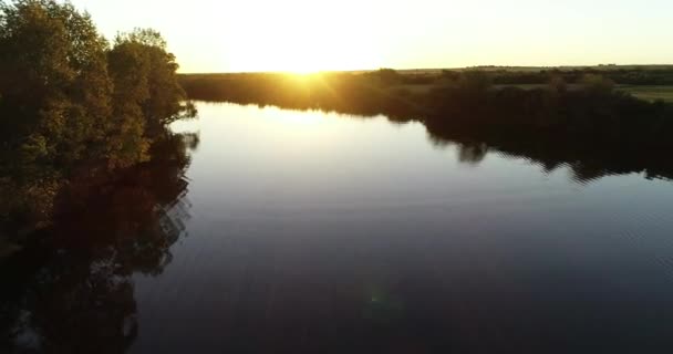 Scène de drone aérien volant au-dessus d'une rivière calme qui monte vers la vue générale du paysage naturel au coucher du soleil. Soleil à l'horizon en arrière-plan. Rivière San Salvador, ville de Dolores, Soriano, Uruguay 