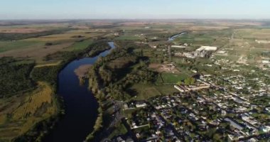 Nehir kıyısındaki şehrin havadan panoramik görüntüsü. Şehir kumaşının üzerinde uçuyor. Backgorund 'da ekinler ve tarım arazisi. Dolores şehri, Soriano, Uruguay