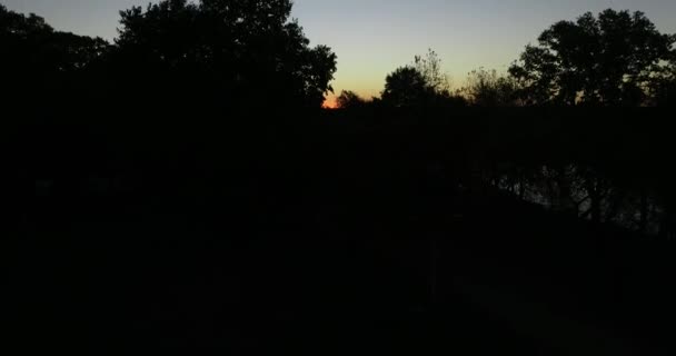 Luchtfoto ontdekken panoramische scène van silhouet van het natuurlijke landschap bij zonsondergang. Hout en rivier en oranje zon aan de horizon. Mooie avond van San Salvador rivier, Dolores stad — Stockvideo