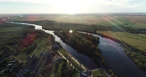 Scène panoramique aérienne de la ville rurale et de la rivière naturelle méandrique au coucher du soleil. Rivière, terres agricoles et soleil en arrière-plan. Rivière San Salvador, ville de Dolores, Uruguay 