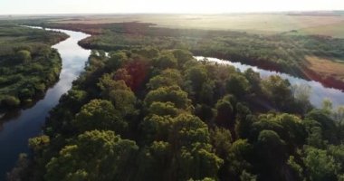 Gün batımında doğal ortamda bir nehir adasının yakınında uçan hava aracı. Su yüzeyinde bulutlar ve gökyüzü yansıması. Arka planda tarım manzarası. Dolores şehri, Soriano, Uruguay