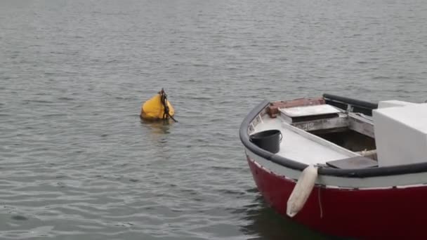 Cámara lenta que muestra el detalle de barco pescador rojo smal amarrado a boya amarilla. Movimiento tranquilo de la superficie del agua. Punta del Este por, Maldonado, Uruguay . — Vídeos de Stock