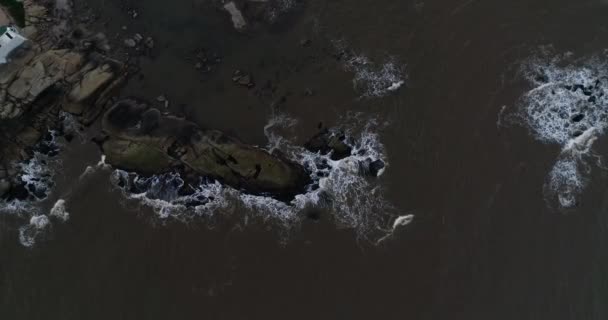 Flygfoto toppscen av vågor stänk mot stenig strand. Nedåtgående visar närbild av vattenflödet över halvön. Jose Ignacio kust, Maldonado, Uruguay — Stockvideo