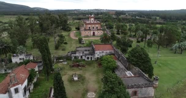 Panoramic aerial of medieval castle and gardens. Flying from ruins towards fortress. Woods and mountains at background. Piria, Piriapolis, Uruguay — Stock Video