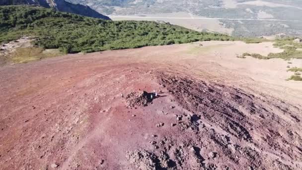 Cerro Colorado 'daki volkanın tepesindeki insanların geniş bir dağ manzarası keşfettikleri insansız hava aracı görüntüsü. Turistik yerleri geziyorum. Sahne dağın tepesinde daireler çiziyor. Neuquen — Stok video