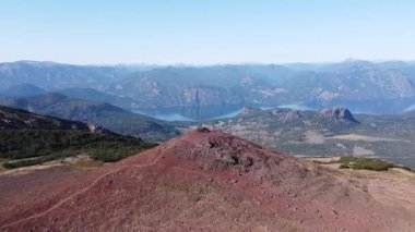 Volkanik dağın tepesinde uçan havadan insanlar dağ zincirleri ve göllerin geniş bir manzarasını keşfediyorlar. Cerro Colorado, San Martin de los Andes, Neuquen, Arjantin