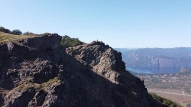 Kayalık Dağ Zirvesi 'nde gölleri ve dağ zincirlerini seyreden genç bir adamın hava aracı görüntüsü. Parallax. San Martin de los Andes, Neuquen, Arjantin