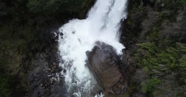 Top-Antenne Nahaufnahme der mächtigen Bewegung des Wassers während des Fallens, Entdeckung während der Drehung des Wasserfalls. Winterwälder im Hintergrund. Cascada de Vullignanco, Neuquen, Argentinien — Stockvideo