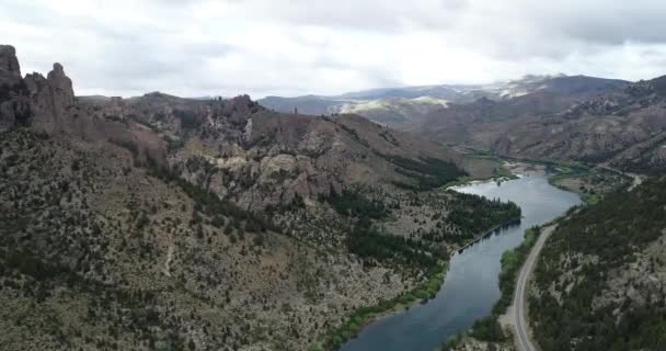 空中无人飞机的场景在纯蓝色的河流上方的高山景观中飞行。山坡上的岩石悬崖和松树林.氧化铝河。美丽的山谷，Valle Encantado, Bariloche, Rio negro. — 图库视频影像