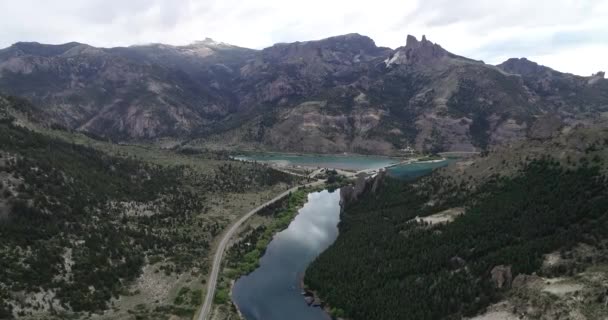 空中无人飞机的场景在纯蓝色的河流上方的高山景观中飞行。山坡上的岩石悬崖和松树林.氧化铝河。美丽的山谷，Valle Encantado, Bariloche, Rio negro. — 图库视频影像