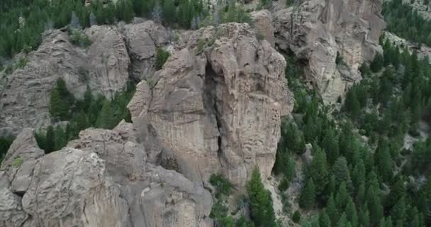 Aerial flying towards rocky structures arising between woods at mountain hillside. Passing near cliffs. Sport spot for climbers, tourism. Valle Encantado, Bariloche. Argentina — Stock Video