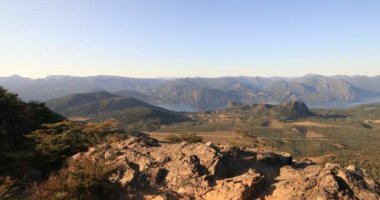 Genç adam dağ zirvesine ulaşıyor lacar gölünün havadan manzarasını keşfediyor, orman ve dağ zincirleri yok. Lanin Ulusal Parkı. Patagonya, Arjantin. San Martin de los Andes