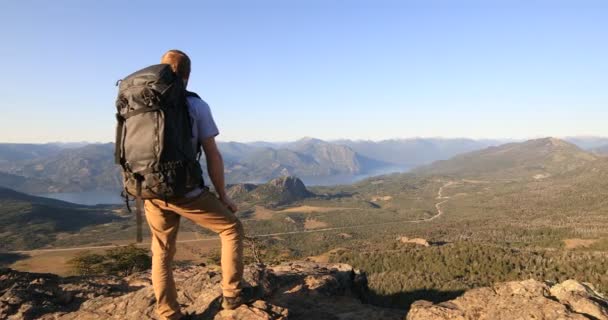 Junger Mann auf dem Gipfel des Berges und starrt auf die luftige Landschaft aus Lacarsee, Nothofagus-Wäldern und Anden-Gebirgsketten. Lanin-Nationalpark. Patagonien, Argentinien. San Martin de los Andes — Stockvideo