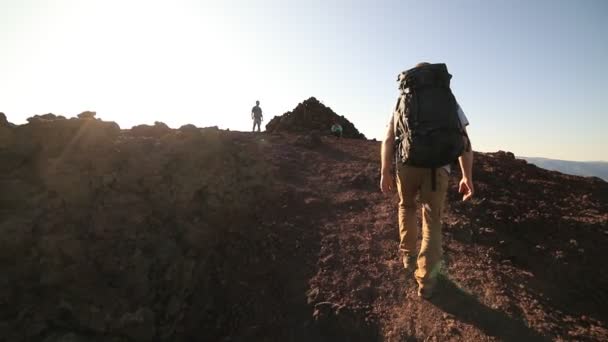 Scena o zwolnionym tempie młodego człowieka dochodzącego do szczytu górskiego, przyjaciół czekających na miejscu przybycia. Rozbłyski, promienie słońca pojawiające się na miejscu. Apacheta z Cerro Colorado. Patagonia, Argentyna — Wideo stockowe