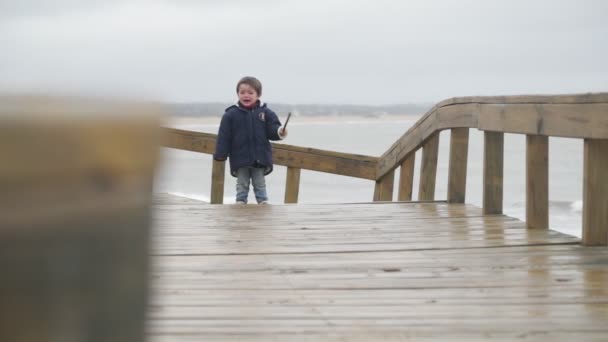 Mișcarea lentă a unui copil trist și furios plângând pe calea lemnului la țărmul mării. Contextul peisajului mării și sandunelor. Jose Ignacio, Rocha, Uruguay — Videoclip de stoc