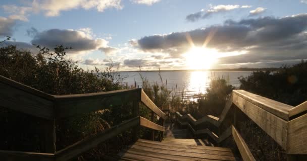 Egy nő sétál le a fa lépcsőn naplementekor. Háttér természetes tengeri lanscape naplementekor turisztikai város. Piriapolis, Uruguay — Stock videók