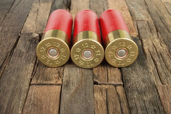 Cartuchos de caça vermelho calibre 12 para espingarda em fundo de madeira . — Fotografia de Stock