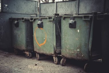 Eski yeşil dumpsters sokakta.