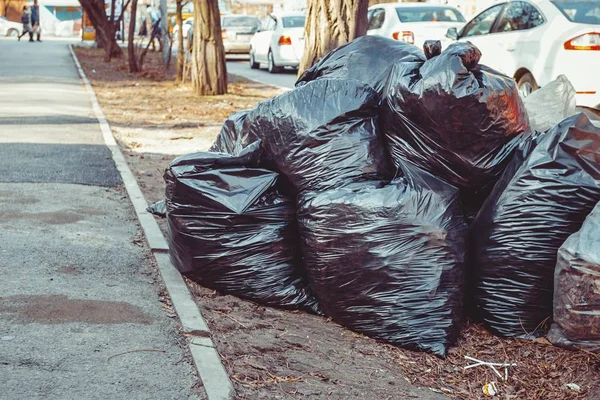 Pile of black garbage bags on sidewalk. — Stock Photo, Image
