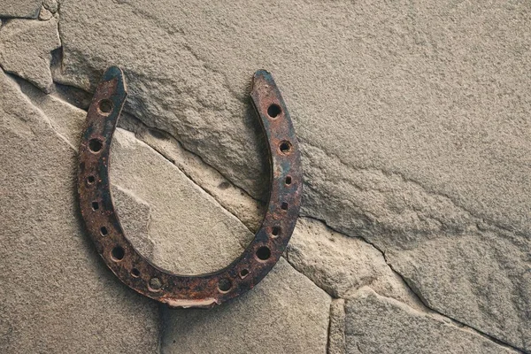 Old rusty horseshoe on natural stone background. — Stock Photo, Image