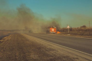 İtfaiyeciler yol boyunca yanan bozkır söndürmek.