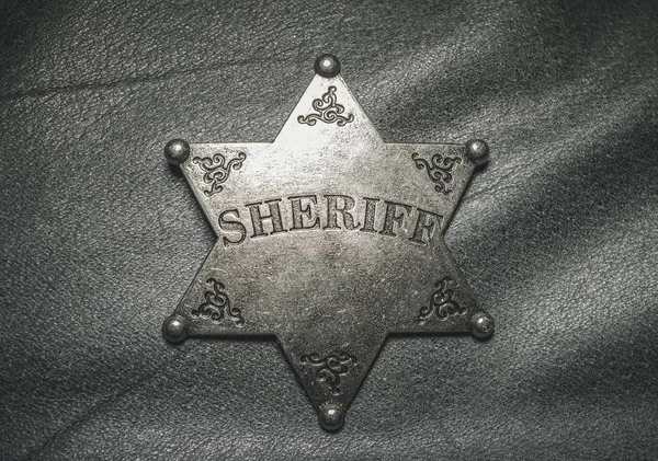 Sheriff badge on gray leather texture background.