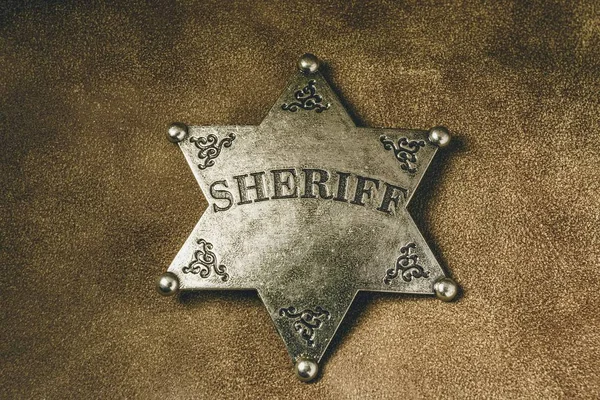 Sheriff badge on brown leather texture background.