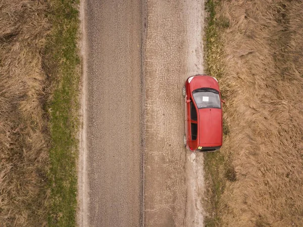 Carro vermelho na estrada do país no tempo da primavera . — Fotografia de Stock