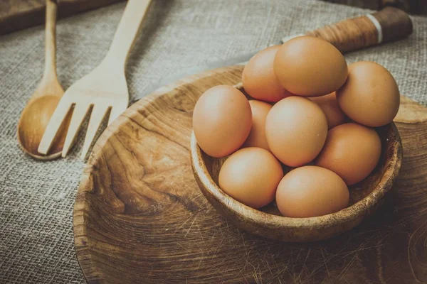 Ovos em uma tigela de madeira na mesa . — Fotografia de Stock