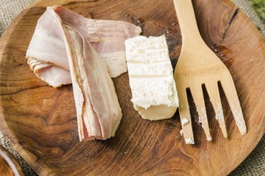 Domuz pastırması şeritler ve tereyağı mutfak aletleri ile ahşap kase.