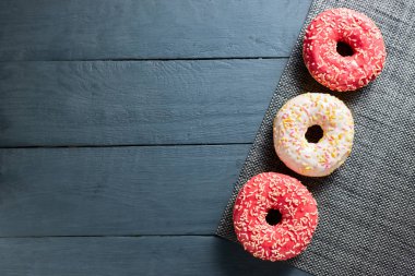 Koyu ahşap arka planda renkli donutlar. Düz yatıyordu. Boşluğu kopyala.