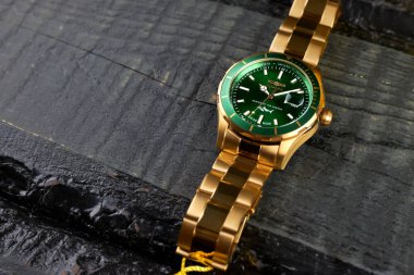 Saint-Petersburg / Rusya - Şubat 2020: Invicta pro dalgıç mens Swiss, Quartz 44mm kol saati yaptı. Siyah ahşap bir masada yeşil kadranlı altın çantalı kol saati..