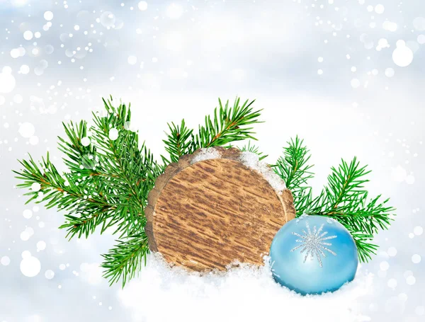 Christmas background. Round wood board, green branch and blue ball