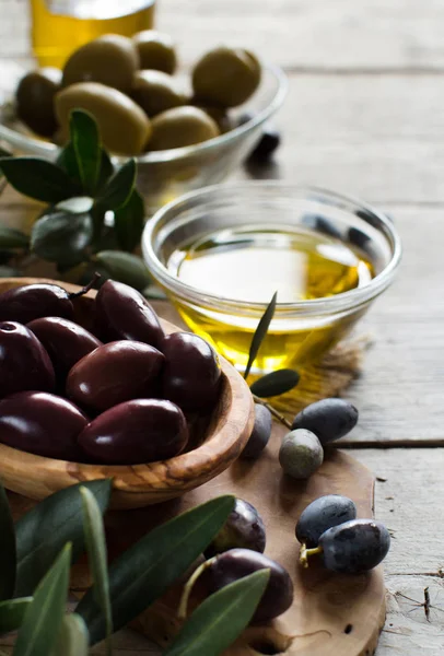 Aceite de oliva y aceitunas sobre fondo de madera — Foto de Stock