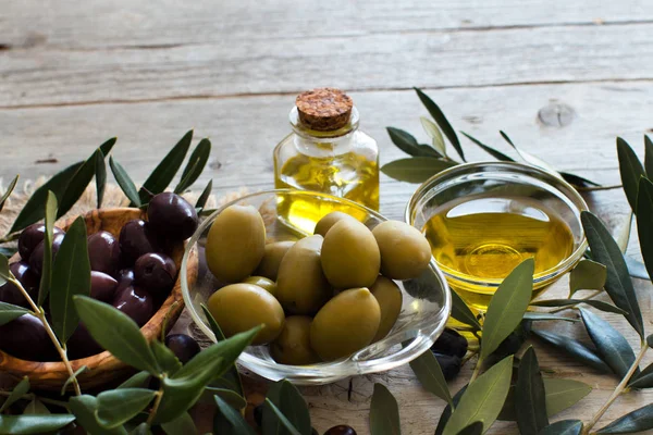 Aceite de oliva y aceitunas sobre fondo de madera — Foto de Stock