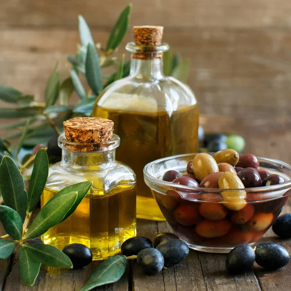 Aceite de oliva y aceitunas sobre fondo de madera — Foto de Stock