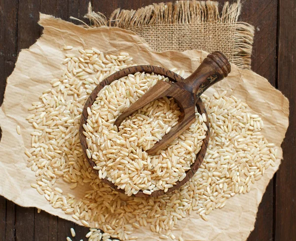 Hromadu hnědá rýže na dřevěné pozadí — Stock fotografie