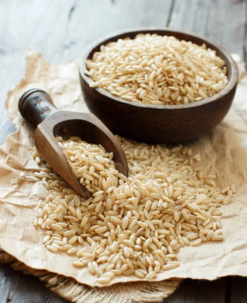 Brązowy ryż w misce z drewnianą łyżką — Zdjęcie stockowe