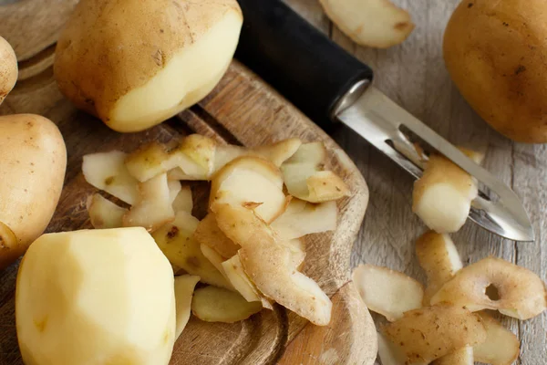 stock image Raw potatoes with a vegetable peeler