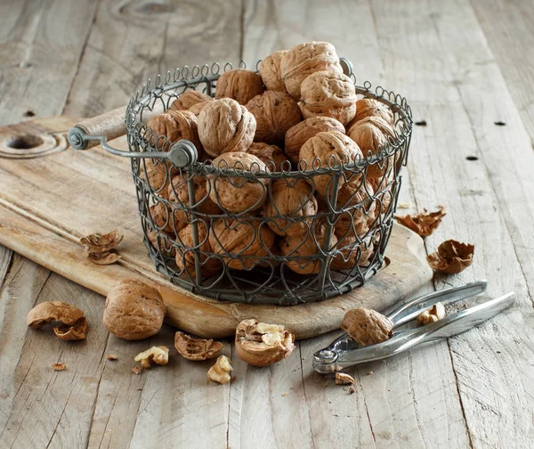 Świeżych orzechów włoskich w koszyku na rustykalnym starym drewnianym stole — Zdjęcie stockowe