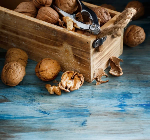 青い木製のテーブル上のボックスで新鮮なクルミ — ストック写真