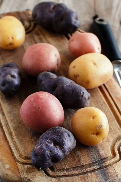 Raw potatoes with a vegetable peeler — Stock Photo, Image