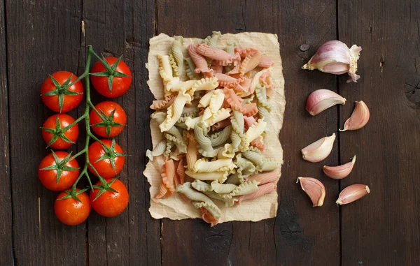 Tricolorní těstoviny, rajčata a česnek — Stock fotografie
